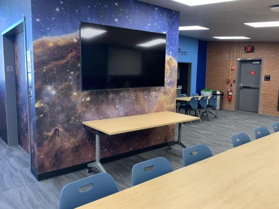 Photo of room with galaxy-print wallpaper and tables with chairs. 