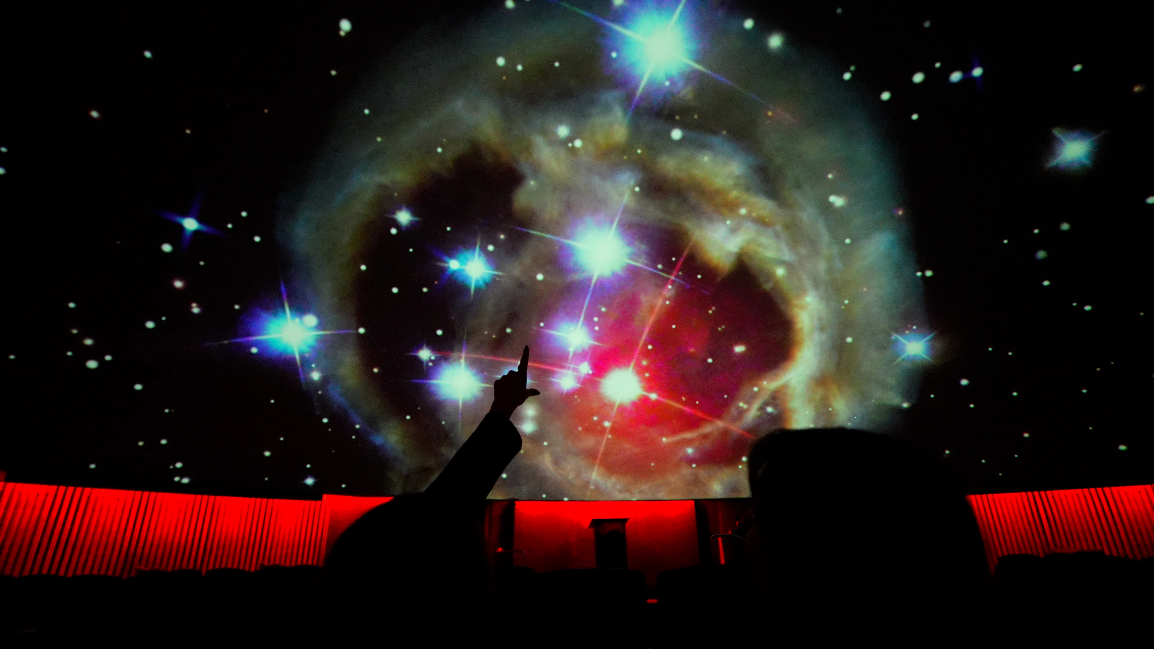 People pointing at the planetarium stars in the dome.